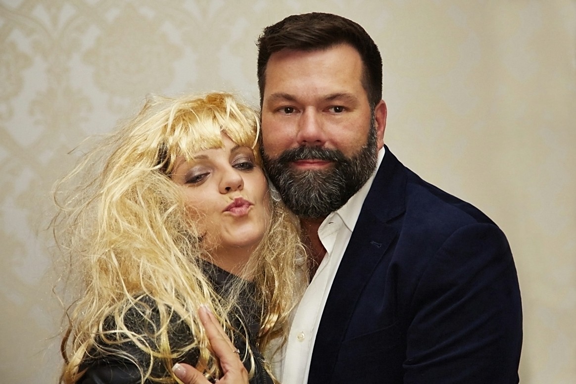 Zwei Gäste mit blonder Perücke posieren lachend in der Fotobox auf einer Feier